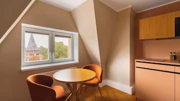 Ein Zimmer mit Esstisch und Stühlen, ein Fenster mit Blick auf ein Gebäude und eine Küchenzeile mit Schränken.