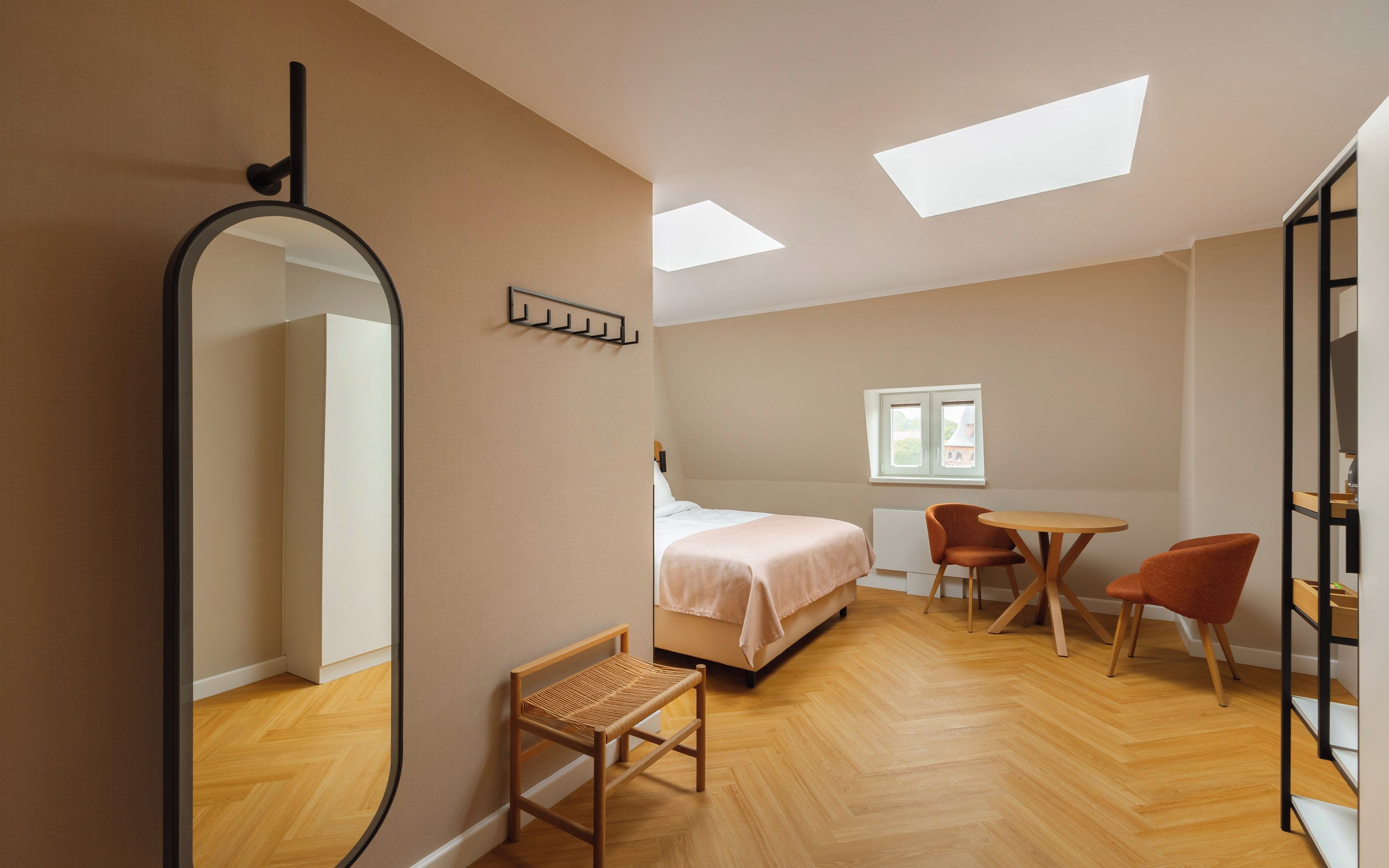 Ein modernes Schlafzimmer mit einem Bett, einem Schreibtisch, zwei Stühlen, einem Spiegel und einem Fenster.