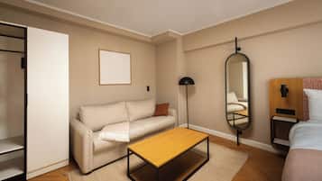 Un dormitorio con un sofá, una pequeña mesa de madera, un espejo y una mesita de noche.