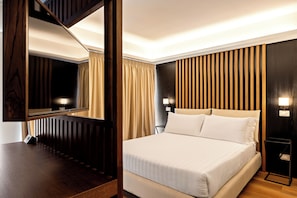 Een hotelkamer met een groot bed, houten lambrisering, een nachtkastje en een spiegel.