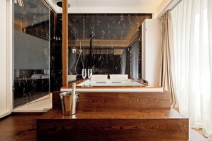Een moderne badkamer met een grote spiegel, een douche en een houten wastafelmeubel met een champagnefles en glazen.