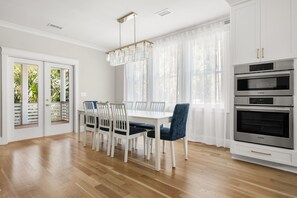 A modern kitchen with white cabinetry, a Bosch oven, and a dining area with a white table and chairs. - Private Pool|Wild Dunes|4 Beds (Isle of Palms)