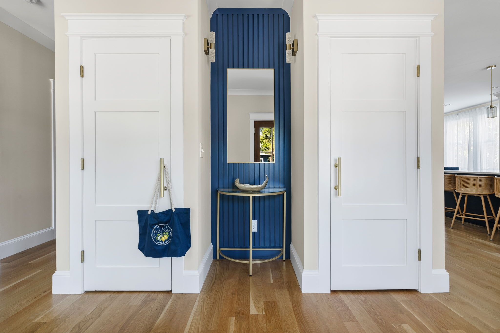 A hallway with two white doors, a blue wall, and a small table with a bowl.