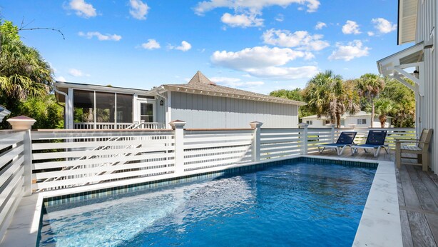 A swimming pool with a white deck, surrounded by a white fence, and a building with a covered deck area. - Private Pool|Wild Dunes|4 Beds (Isle of Palms)
