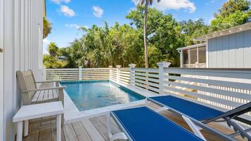A pool area with a wooden deck, white railings, and a covered seating area.