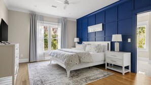 A bedroom with a bed, nightstands, a dresser, a ceiling fan, and a window with curtains. - Private Pool|Wild Dunes|4 Beds (Isle of Palms)