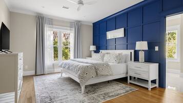 A bedroom with a bed, nightstands, a dresser, a ceiling fan, and a window with curtains.
