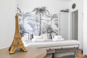 A bedroom with a bed, a nightstand, and a decorative Eiffel Tower model.