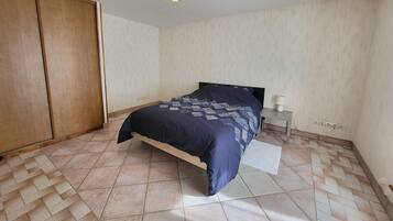 A bedroom with a bed, a nightstand, a wardrobe, and a ceiling light fixture.