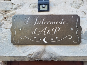 Une plaque en pierre, ornée de motifs sculptés et d’éléments décoratifs, fixée à un mur à texture.