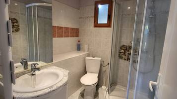 Een moderne badkamer met een douchecabine van glas, een wit wastafeltje en een toilet.