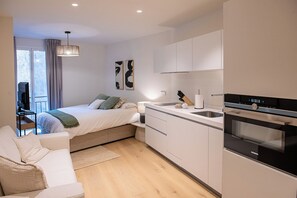 Eine moderne Wohnung mit Bett, Küchenzeile und Essbereich.