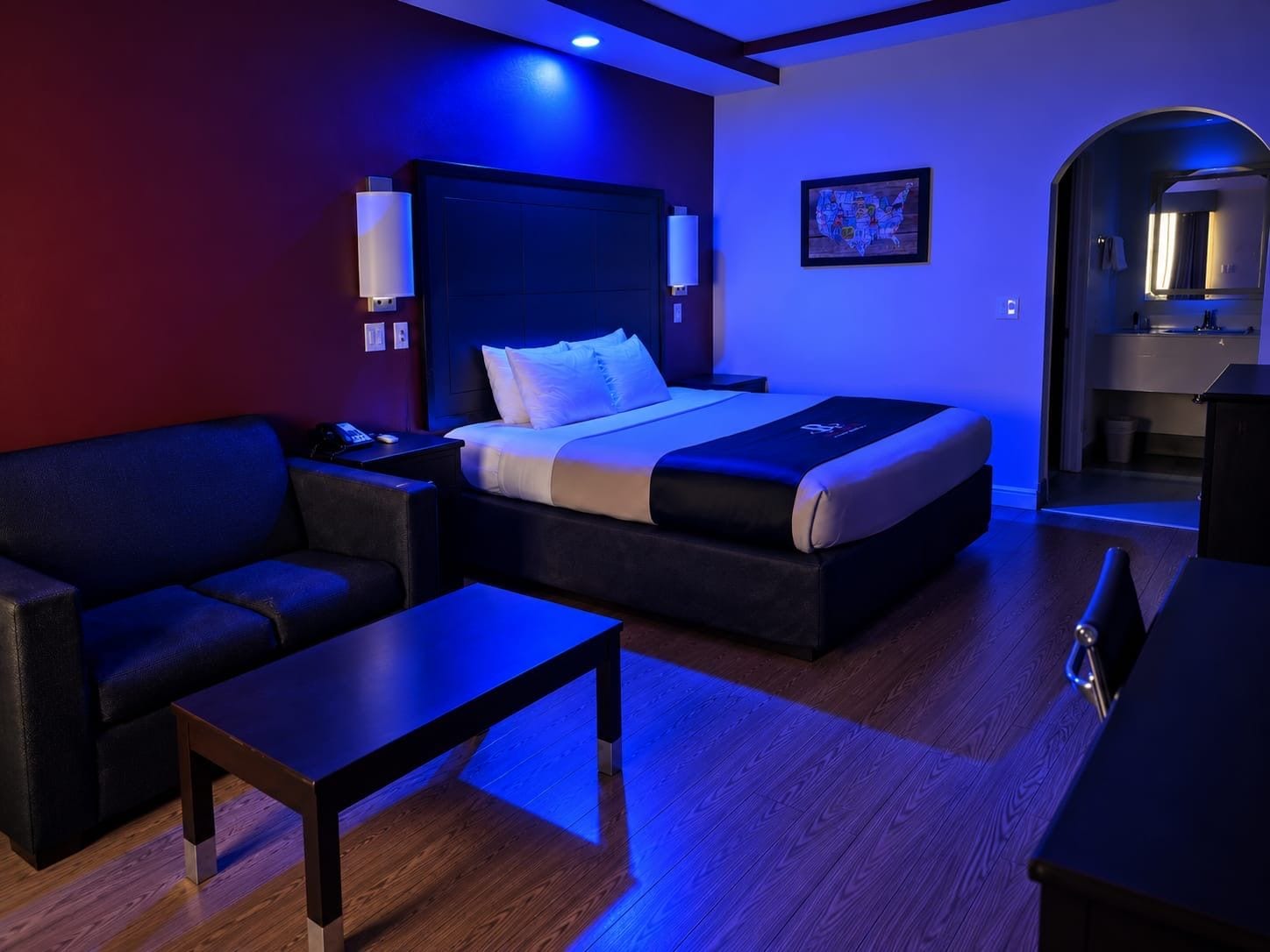 A modern hotel room with a bed, a sofa, a small table, and a desk.