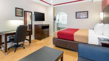 A hotel room with a bed, desk, chair, and a TV.