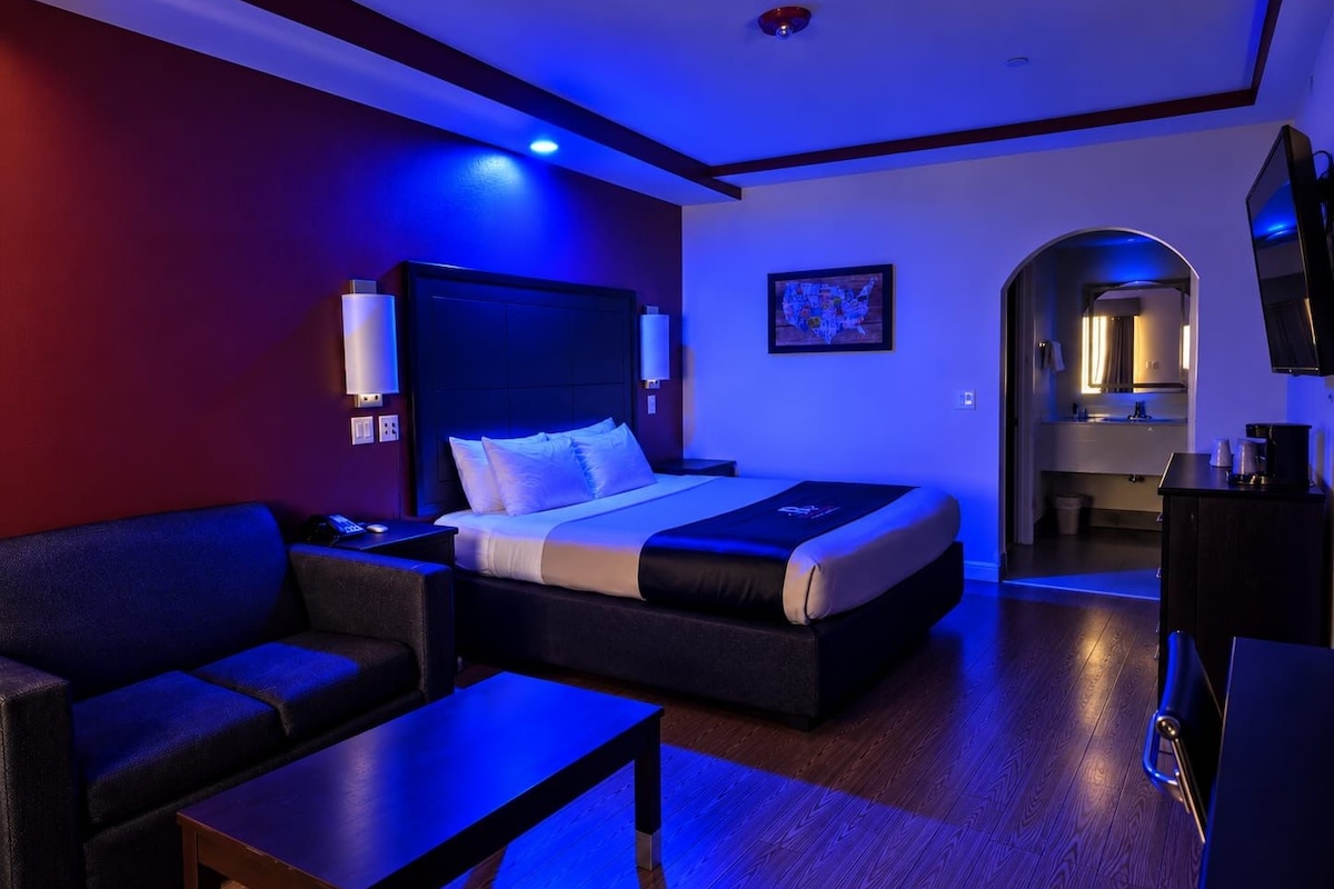 A hotel room with a bed, a sofa, a coffee table, and a TV.
