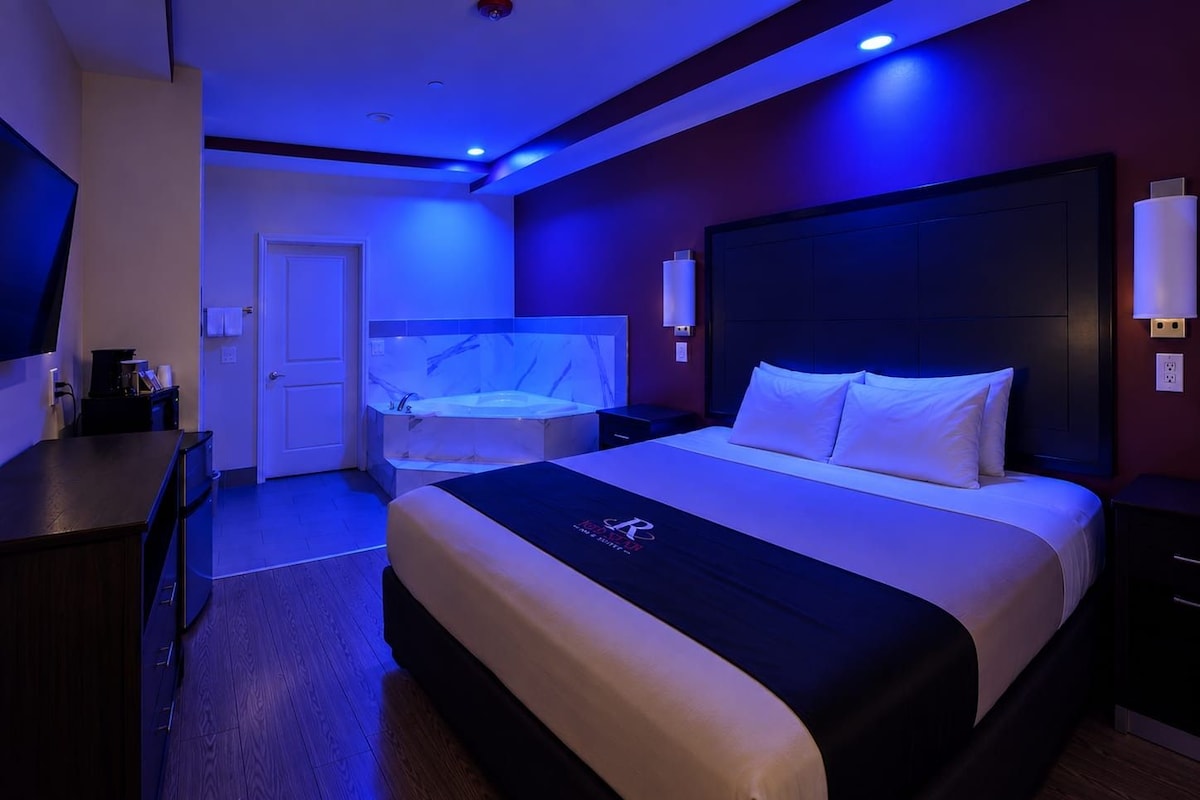 A hotel room with a bed, a desk, a television, and a bathroom with a bathtub.