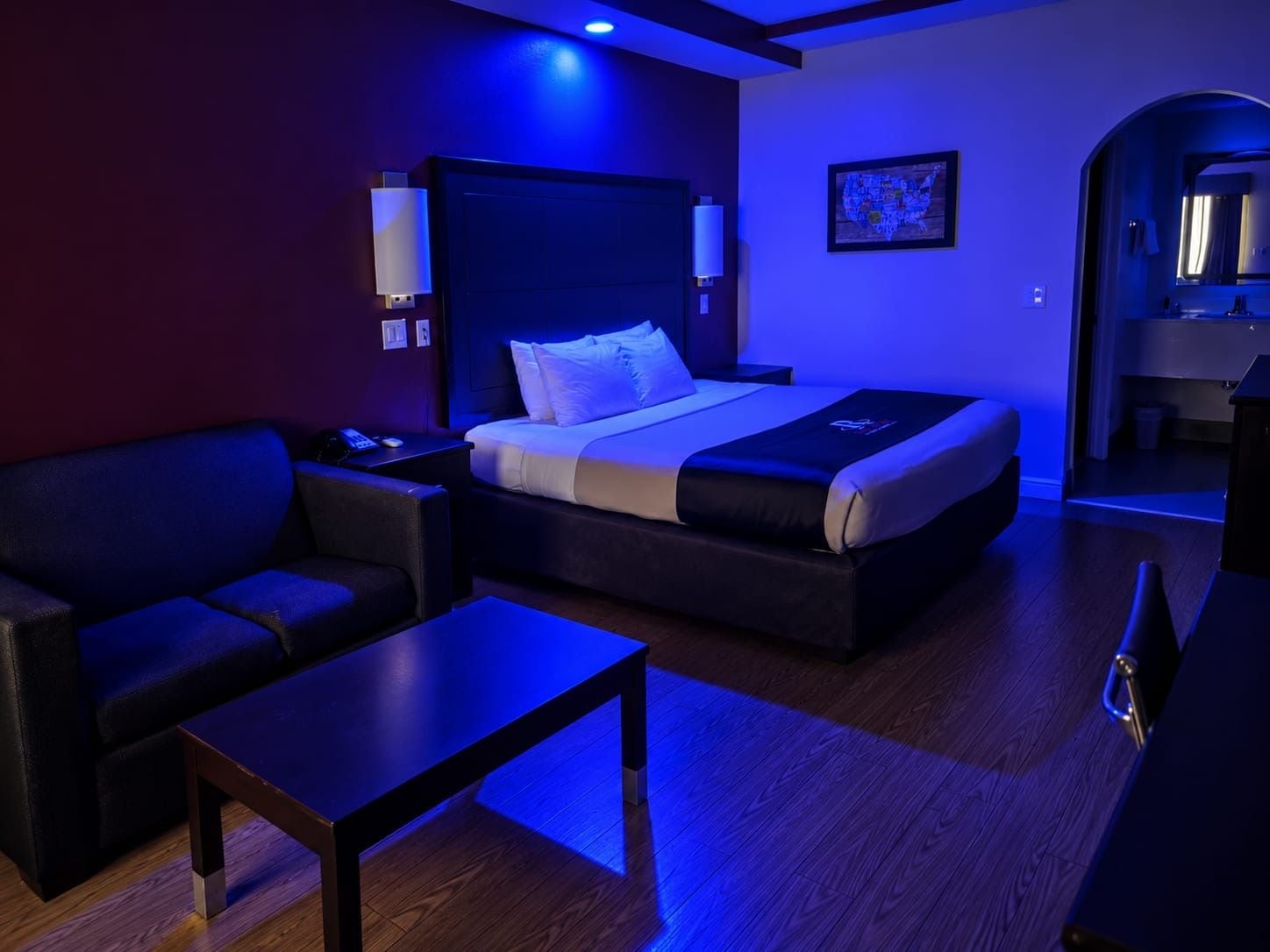 A modern hotel room with a bed, a sofa, a small table, and a desk.