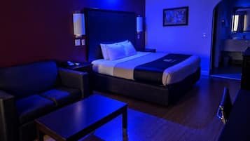 A modern hotel room with a bed, a sofa, a small table, and a desk.