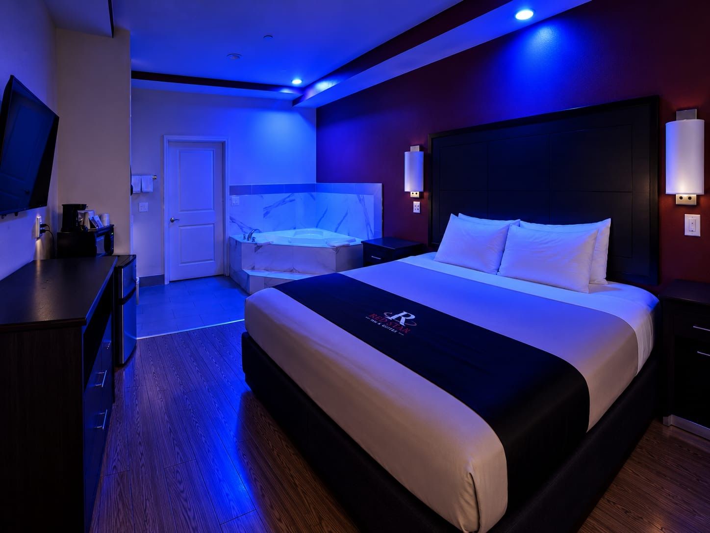 Una habitación de hotel con una cama, un escritorio, un televisor y un baño con bañera.