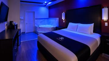A hotel room with a bed, a desk, a television, and a bathroom with a bathtub.