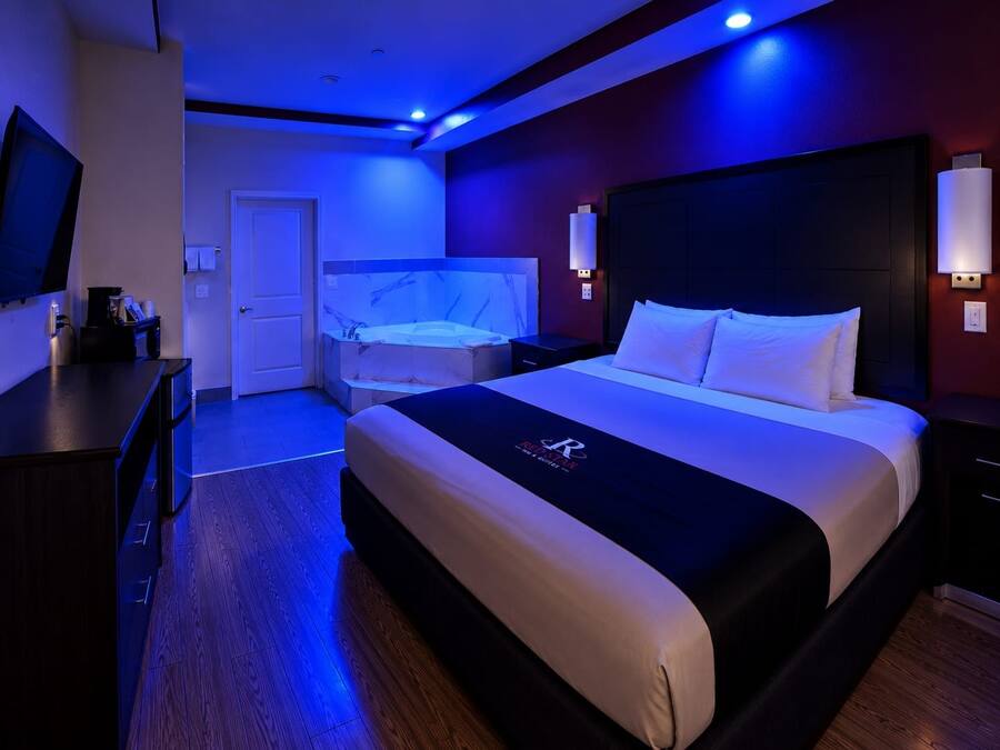Ein Hotelzimmer mit Bett, Schreibtisch, Fernseher und einem Badezimmer mit Badewanne.