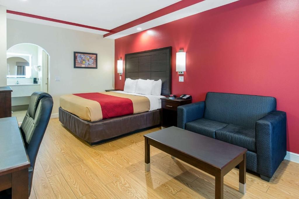 Une chambre d’hôtel avec un lit, un canapé, un bureau et une table de chevet.
