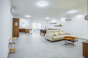 A spacious living area with a sofa, a coffee table, and a dining area with chairs and a table. - Modern Maisonette with Pool in Gharghur (Ħal Għargħur)