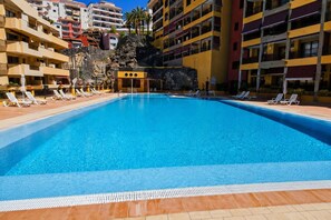 Ein Swimmingpool mit Liegestühlen und einer Steinmauer im Hintergrund.