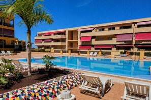 A hotel pool area with a clear blue pool, lounge chairs, and a colorful mosaic border. - Olivia Playa La Arena (Puerto de Santiago)