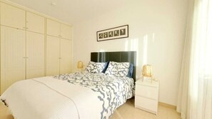 Een slaapkamer met een bed, nachtkastjes, een kledingkast en een aan de muur hangend schilderij.
