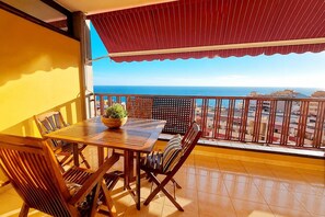 A balcony with a table and chairs, a potted plant, and a view of the sea. - Olivia Playa La Arena (Puerto de Santiago)