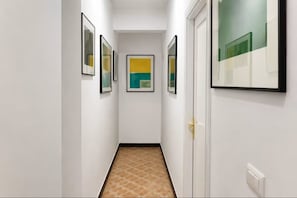 A hallway with framed artwork on the walls, a door on the right, and a tiled floor. - VV Vacation Health 2 (Santa Cruz de Tenerife)