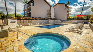 Um hotel com piscina, espreguiçadeiras e área ajardinada com palmeiras.