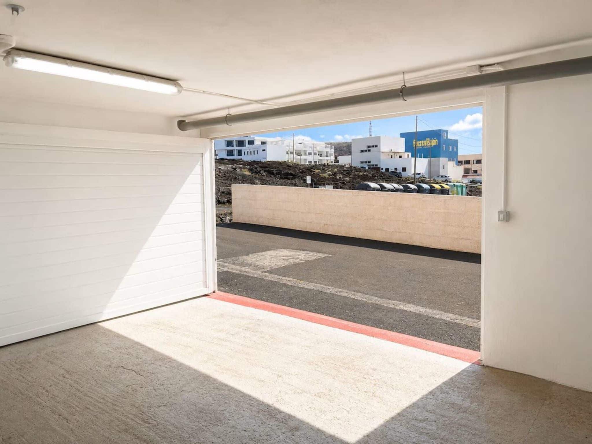 A parking garage entrance with a concrete floor and a white garage door.