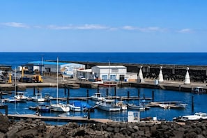 Ein Yachthafen mit vertäuten Booten, ein Gebäude mit blauem Dach und ein klarer, blauer Himmel.