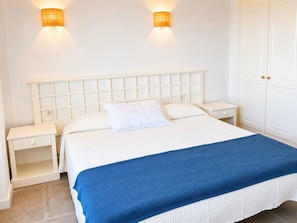 A bed with a white headboard, two bedside tables, and a blue blanket.
