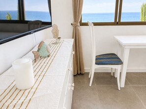 Ein Zimmer mit einem Bett, einem Sessel, einem Tisch und Meerblick.