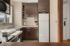 A compact kitchen with a built-in microwave, a sink, and a refrigerator. - Bluehorizonbenalmadena Apartment with Pool, Private Terrace, and Wi-Fi (Benalmádena)