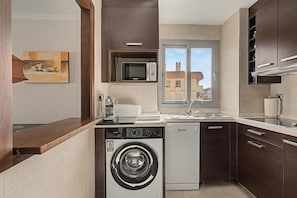 A compact kitchen with a washing machine, a microwave, and a sink. - Bluehorizonbenalmadena Apartment with Pool, Private Terrace, and Wi-Fi (Benalmádena)