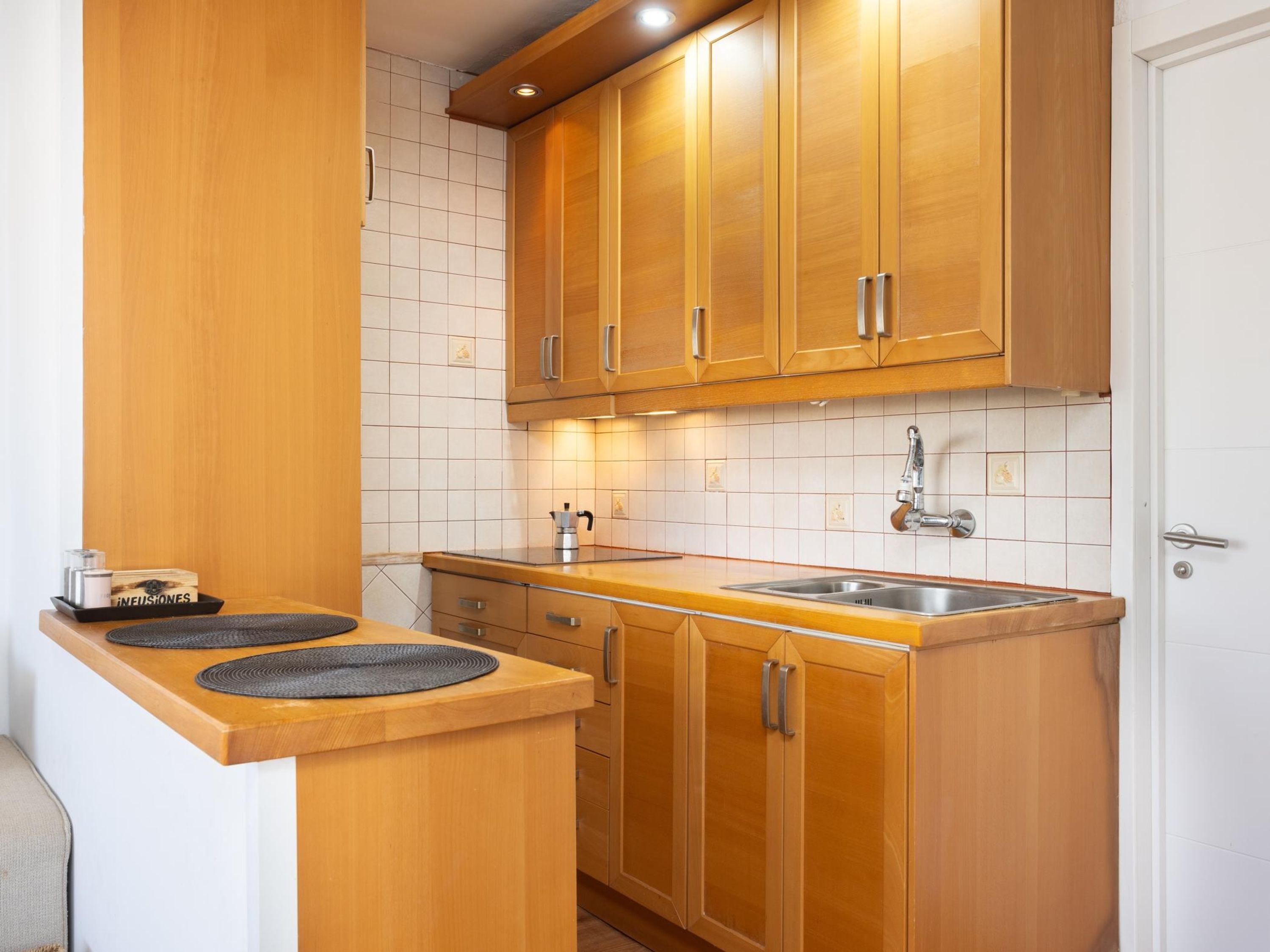 Eine Küche mit Holzschränken, einer Edelstahlspüle und einer Arbeitsplatte mit Kaffeemaschine.