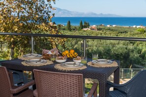 Ein gedeckter Tisch mit Blick auf das Meer und die dahinterliegenden Hügel.