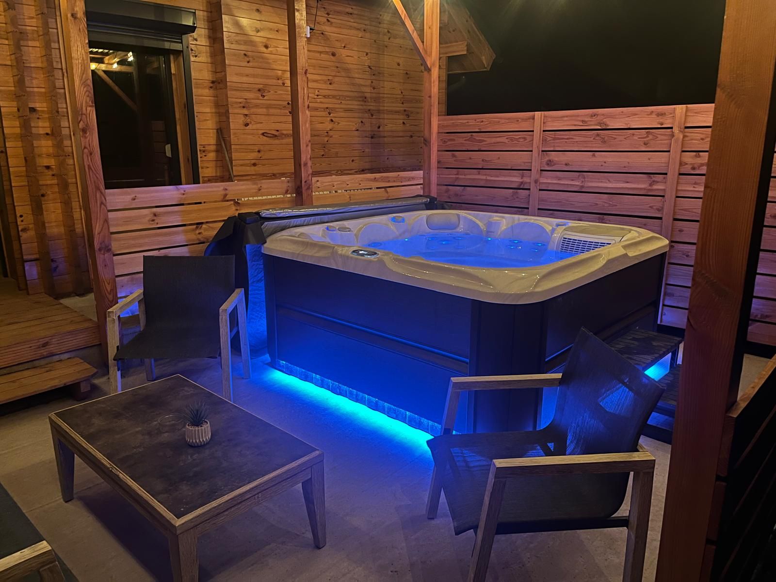 Ein Whirlpool in einer Holzhütte mit Tisch und Stühlen.