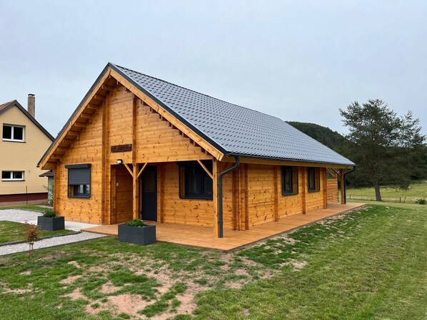 A wooden cabin with a sloped roof, a porch, and a small deck.