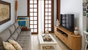 A living room with a sofa, coffee table, TV stand, and decorative items. - Maria Ines Bondesan (ubatuba)