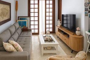 Una sala de estar con sofá, mesa de centro, mueble para televisor y objetos decorativos.