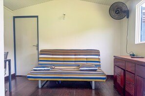 A room with a sofa, a door, a wall fan, and a window. - L'Oasis dans le Désert - à 350 m de la plage (Sainte-Luce)