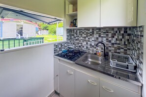 A compact kitchen with a gas stove, a sink, and a tiled backsplash. - L'Oasis dans le Désert - à 350 m de la plage (Sainte-Luce)