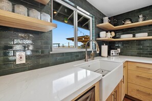 A modern kitchen with a white countertop, dark backsplash, and wooden cabinets. - Desert Shadow A 10ac Retreat w/Pool + Hot Tub+ Pickleball + Archery + More (Yucca Valley)