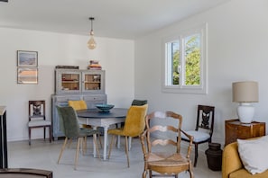 A dining area with a table, chairs, and a cabinet. - Mi Casa Blanca - piscine privée (La Teste-de-Buch)