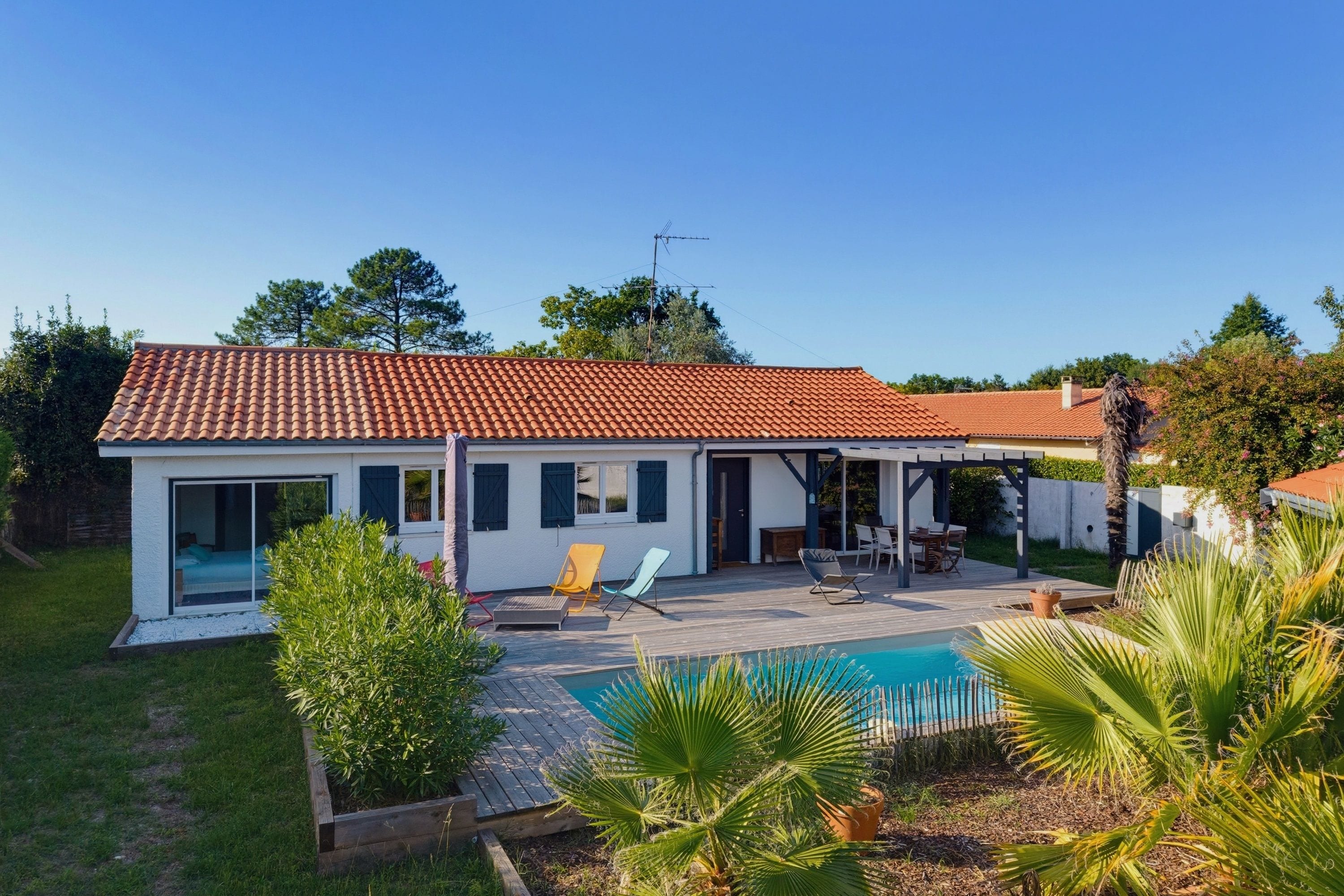 A house with a tiled roof, a swimming pool, and a covered patio area.